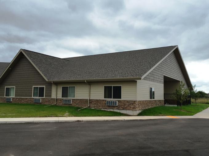 A residential house with a sloped roof and surrounding lawn.