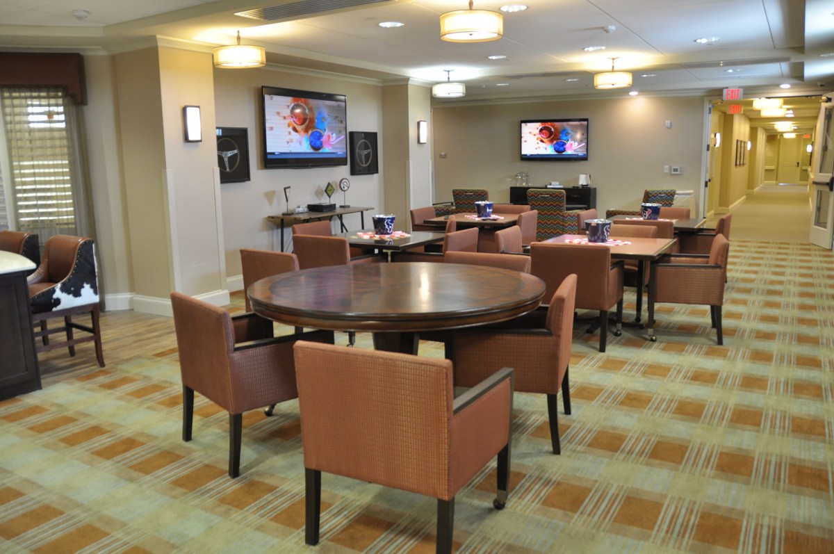 A modern conference room with round tables, comfortable chairs, and wall-mounted televisions.
