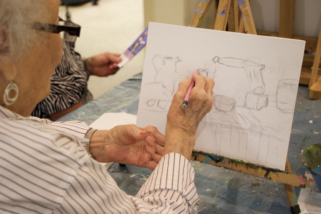 An artist working on a pencil sketch on canvas, focusing on their art.