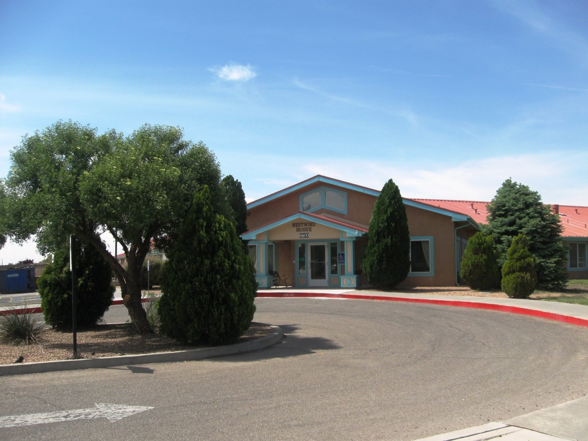 A building with a red roof surrounded by trees on a sunny day.