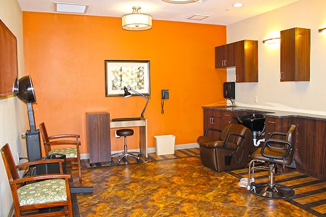 Modern salon interior with an orange accent wall and hair styling station.