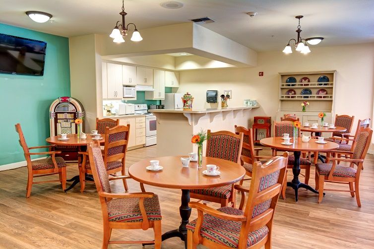 A cozy dining area with wooden tables and chairs, adjacent to a kitchen space.
