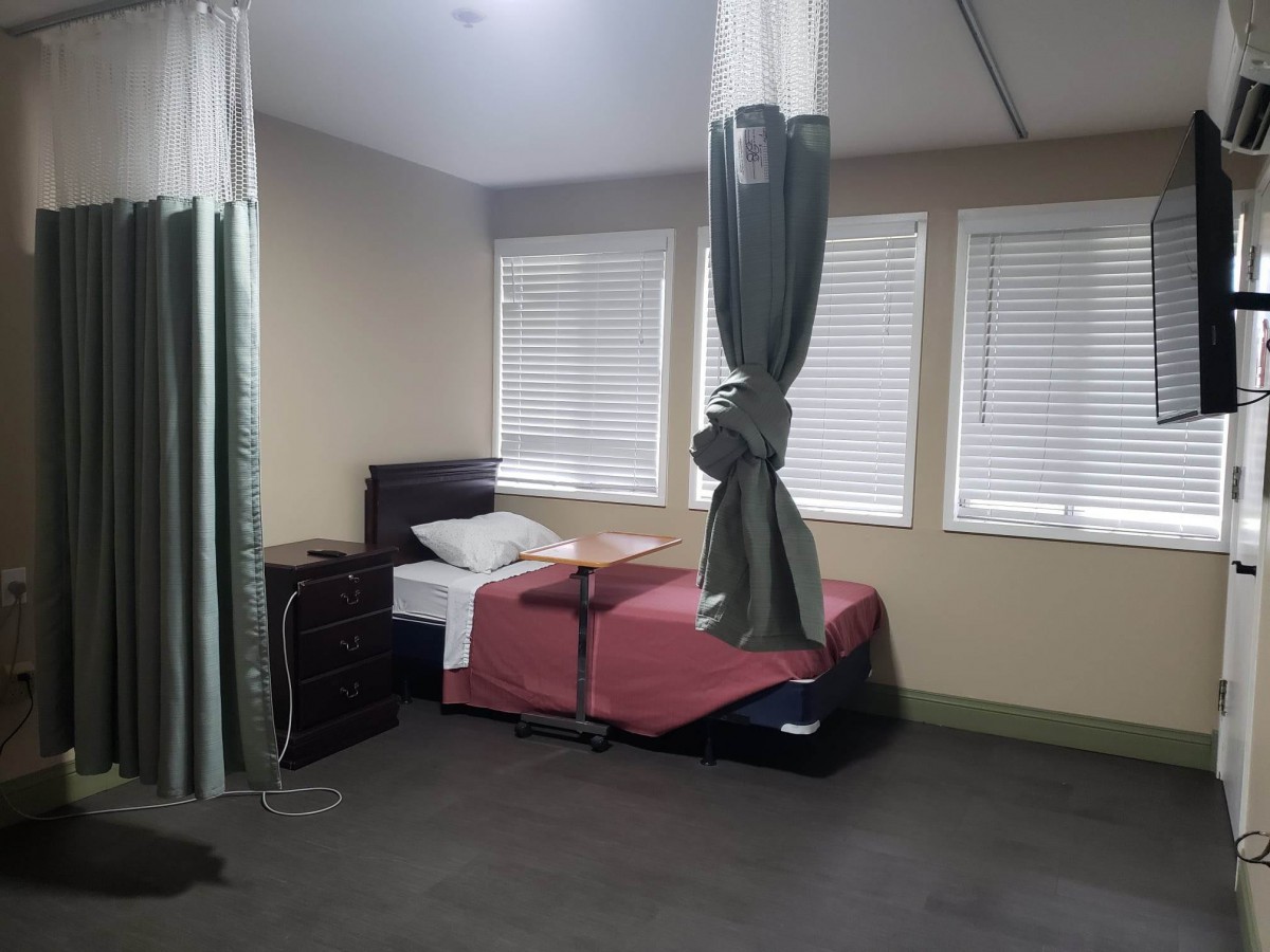 A hospital room featuring a single bed with privacy curtains.