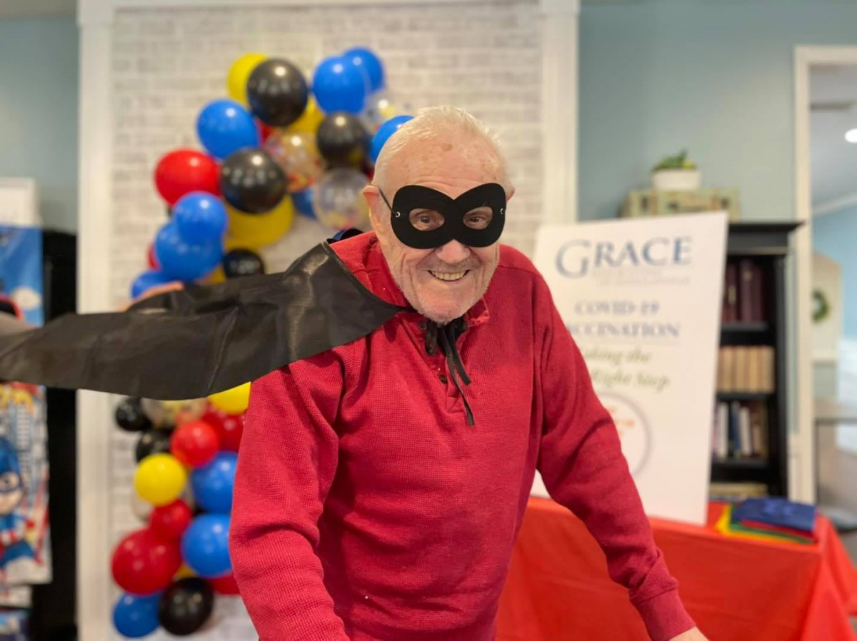 A person dressed in a superhero costume with a mask and cape, standing in front of colorful balloons.