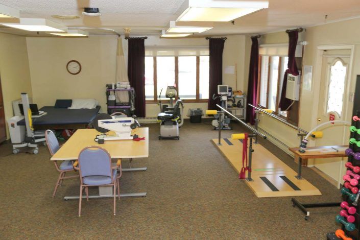 A physical therapy clinic equipped with exercise machines and parallel bars.