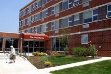 A red brick apartment building with a landscaped entrance and an awning.