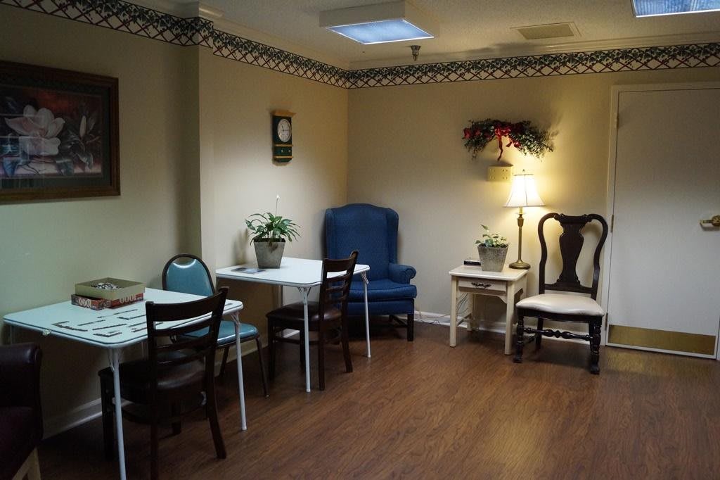 A cozy living room with a mix of chairs, tables, and decorative plants.