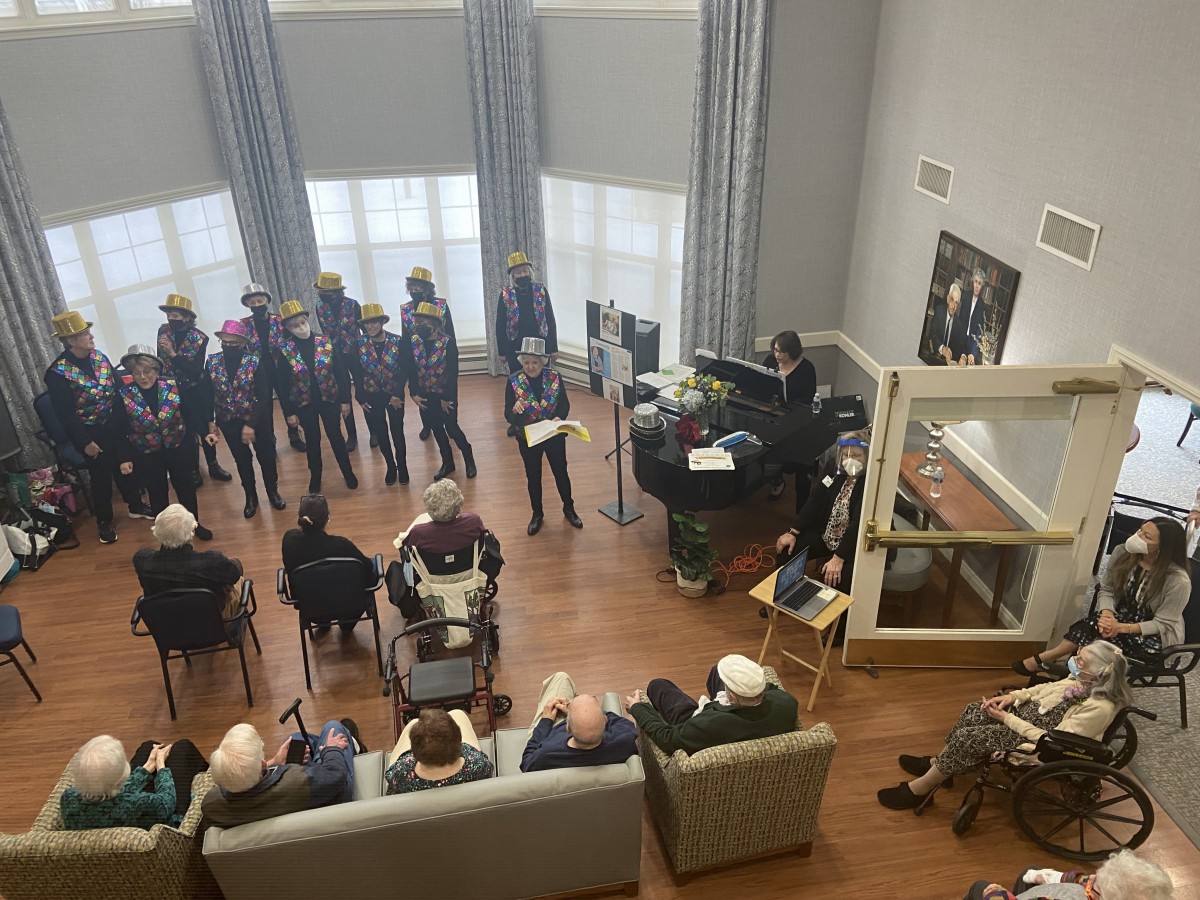 A band performs indoors for an audience seated in a cozy room.
