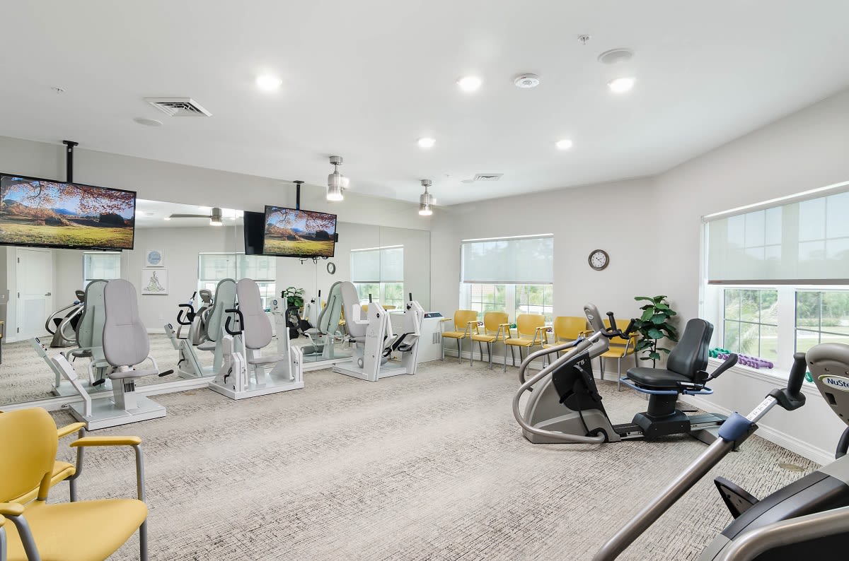 A well-lit gym with various fitness equipment including treadmills and stationary bikes.