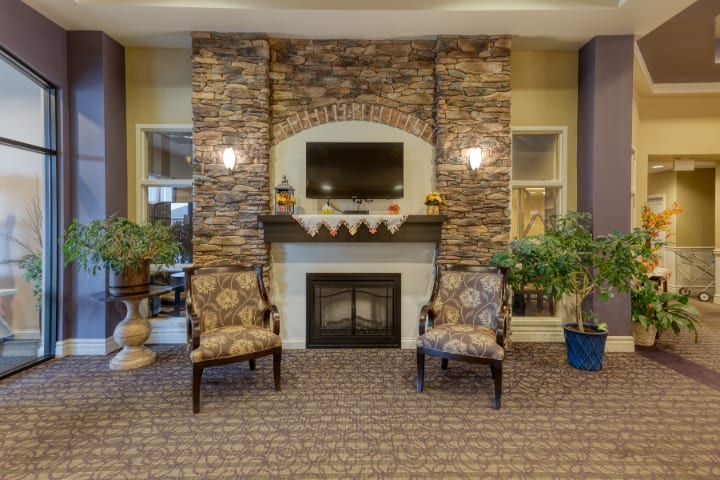A cozy living room with a stone fireplace, television, and comfortable armchairs.