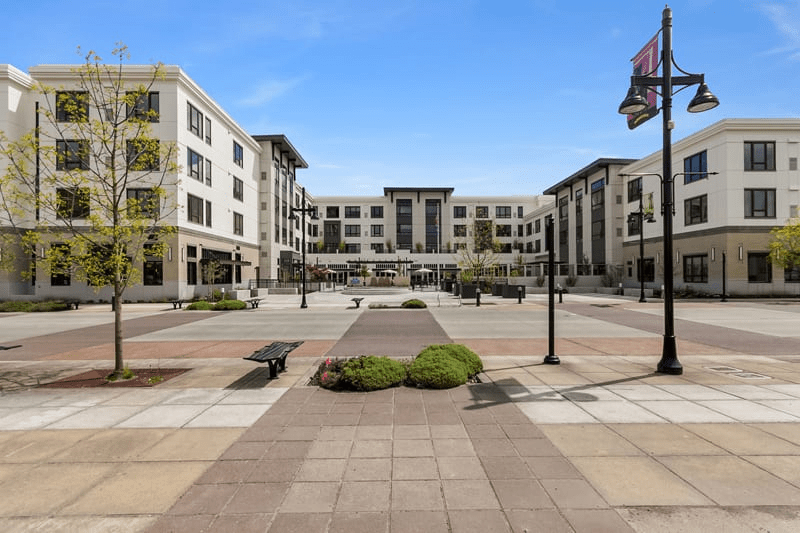 A modern residential complex with a spacious central plaza and landscaping.