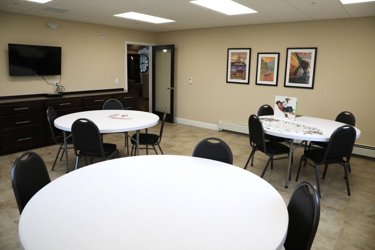 An empty conference room with round tables, chairs, and artwork on the walls.