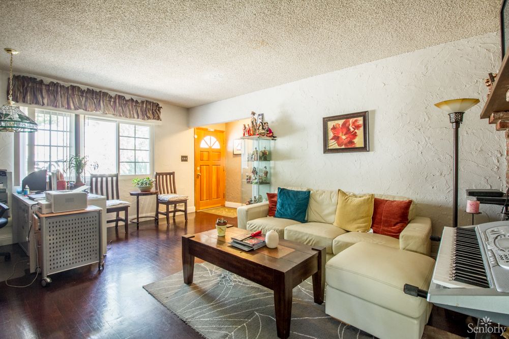 A cozy living room with a sectional sofa, colorful pillows, a coffee table, and wall art.