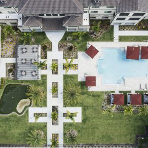 Aerial view of a residential complex featuring a swimming pool and landscaped garden areas.