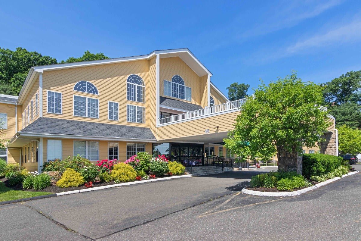 A modern hotel building with attractive landscaping and a spacious parking area on a clear day.