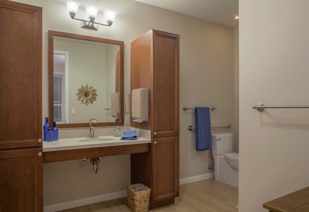 A modern bathroom interior featuring a wooden finish with a sink, mirror, and neatly arranged towels.