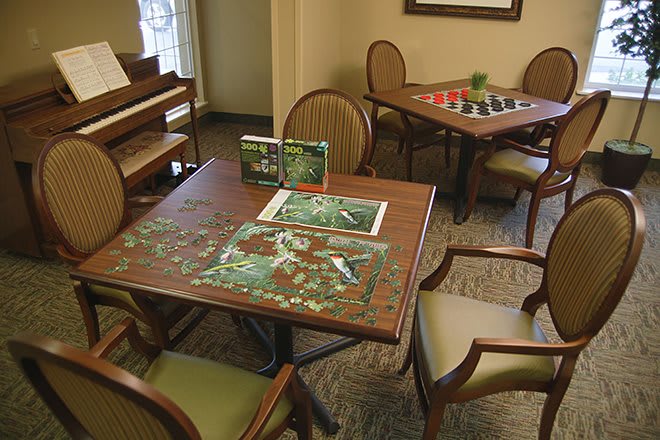 A cozy indoor setting with tables and chairs, featuring a partially completed jigsaw puzzle and board games.
