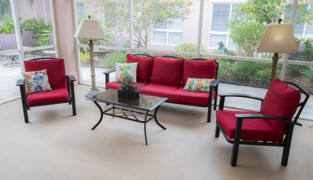 A cozy living room with red-cushioned seating and a glass coffee table.