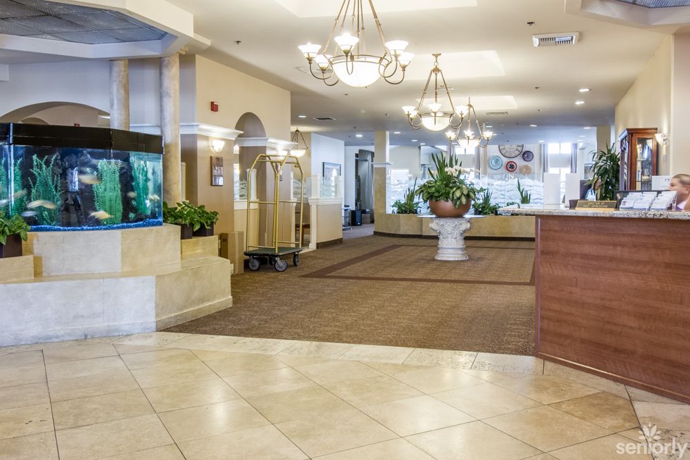 Bright hotel lobby with chandeliers and reception desk.