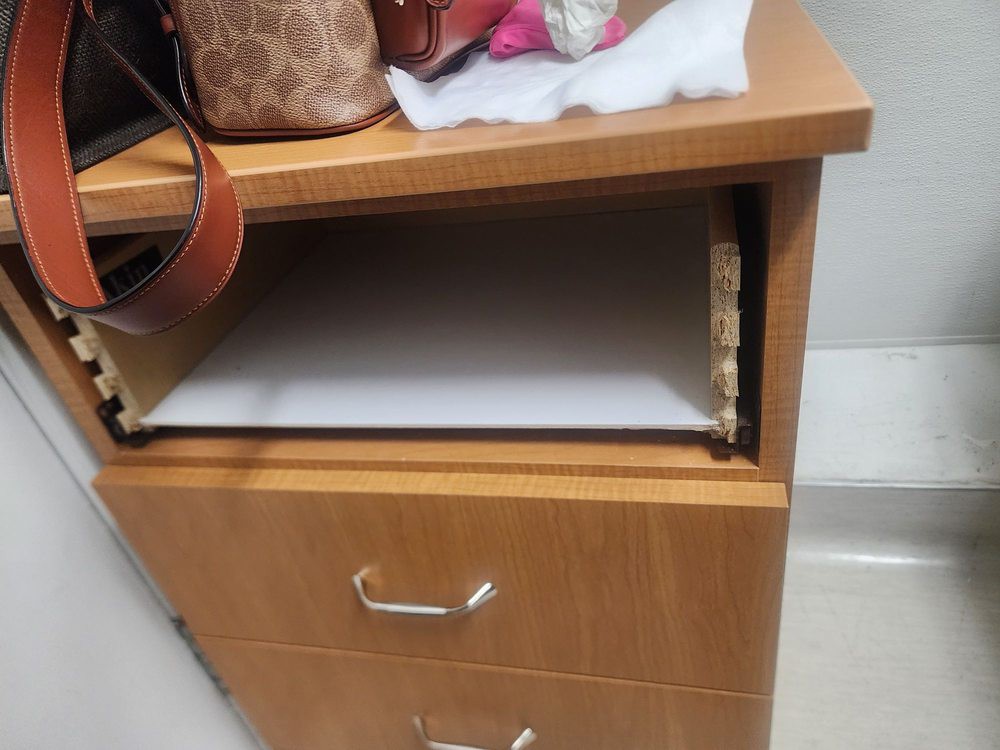 An open drawer in a wooden cabinet with items on top.