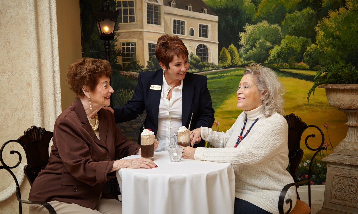 Three women enjoying drinks and conversation at a table indoors.