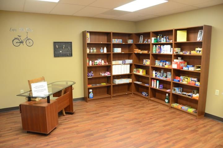 A small store with wooden shelves displaying various products.