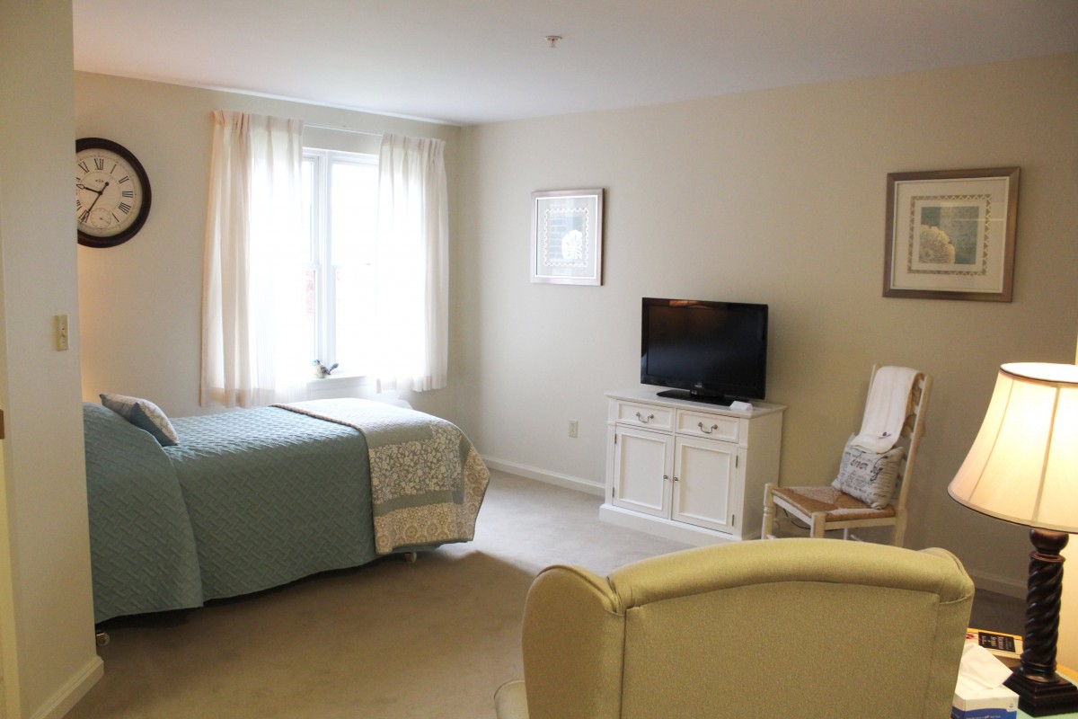 A cozy bedroom with a bed, TV, and seating area.