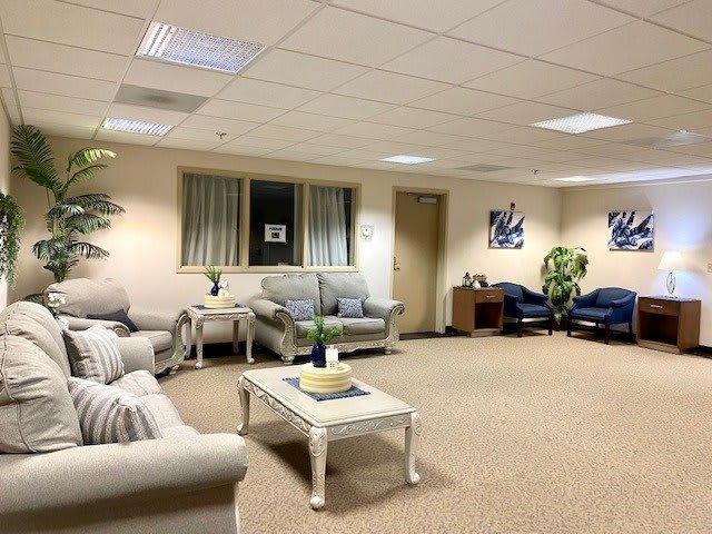 A spacious waiting room with sofas, chairs, and a table in a well-lit setting.