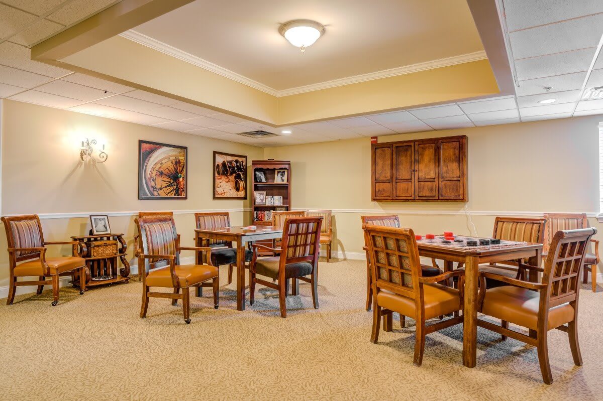 A cozy dining room with wooden tables and chairs, adorned with artwork on the walls and soft ceiling lighting.