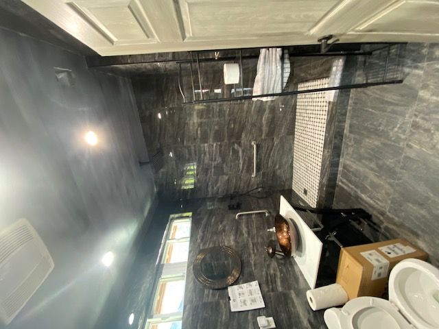 A modern bathroom with dark tiled walls and sleek fixtures.