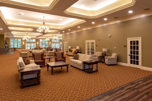 A spacious and elegantly designed lounge area with comfortable seating, warm lighting, and a decorative chandelier.
