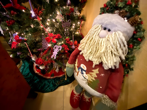 A festive Santa Claus decoration stands beside a beautifully adorned Christmas tree.