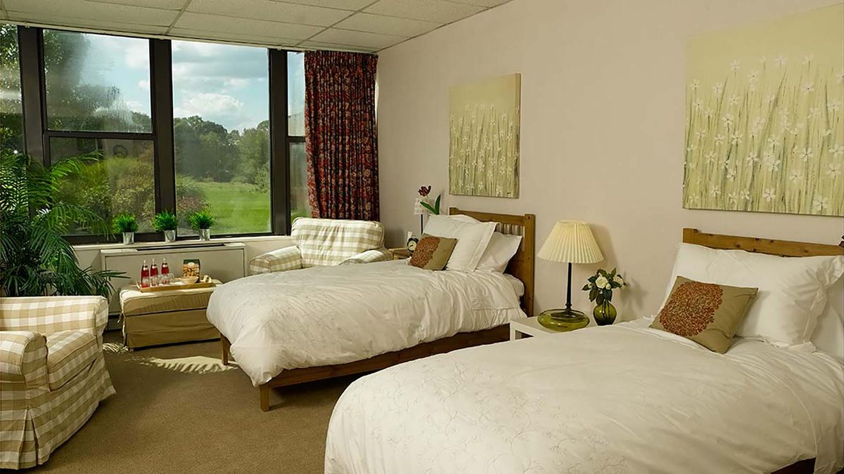 A cozy hotel room featuring two neatly made beds, a window with a scenic view, and tasteful decor.
