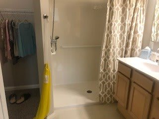 A bathroom with a shower, curtain, and cabinet.