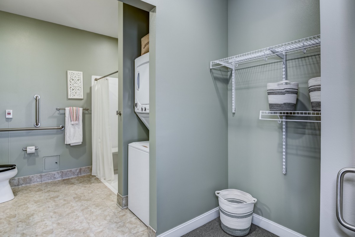A compact laundry and bathroom space with a washer, dryer, and storage shelves.