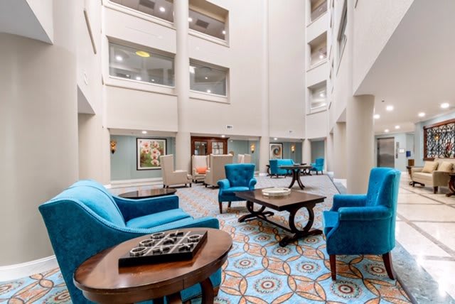 A spacious and modern lobby area with blue armchairs and a decorative patterned floor.