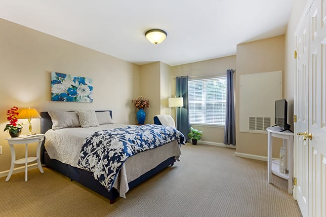 A cozy bedroom interior with a large bed, a window with curtains, and decorative elements.