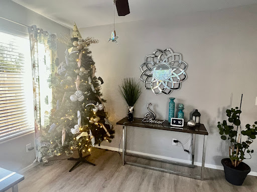 A beautifully decorated living room featuring a Christmas tree, stylish decor, and a modern mirror.