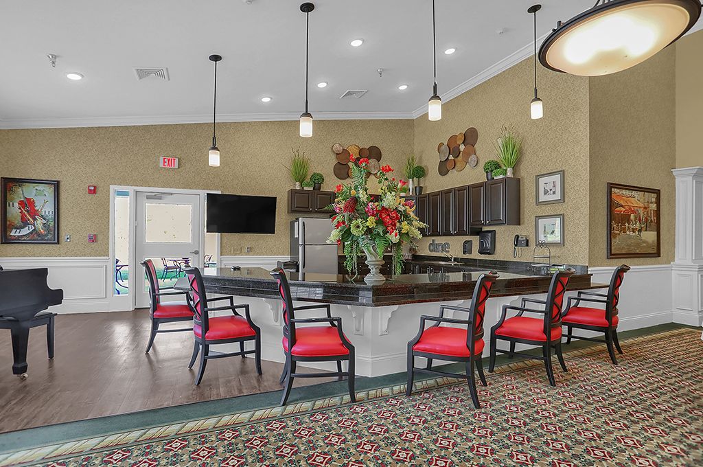A modern kitchen and seating area featuring pendant lighting and vibrant red chairs.