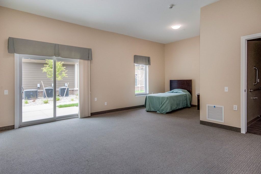 A spacious bedroom with a single bed and large windows allowing natural light.