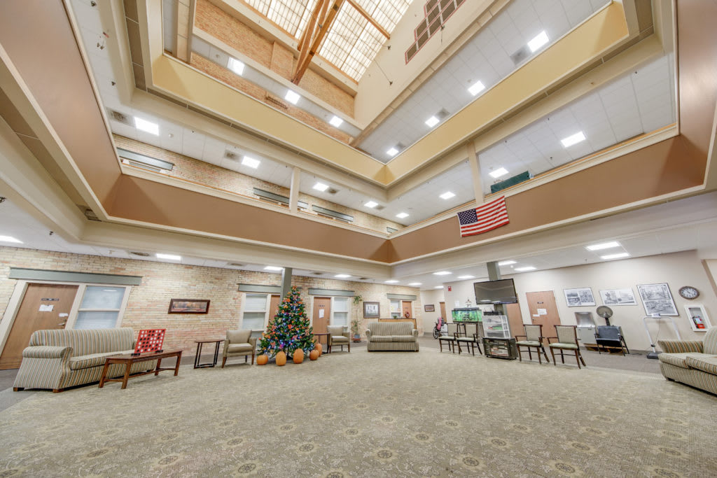 A spacious atrium with multiple levels, featuring comfortable seating, decorative elements, and a skylight overhead.