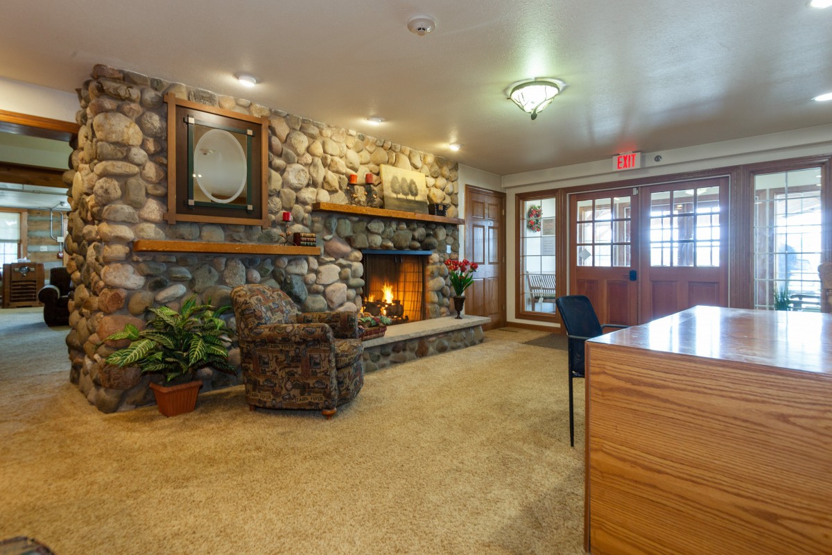 A cozy lounge featuring a rustic stone fireplace and comfortable seating.