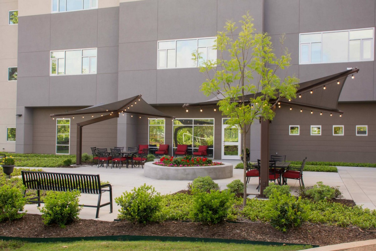 A modern patio featuring comfortable seating, pergolas, and well-maintained landscaping outside a building.