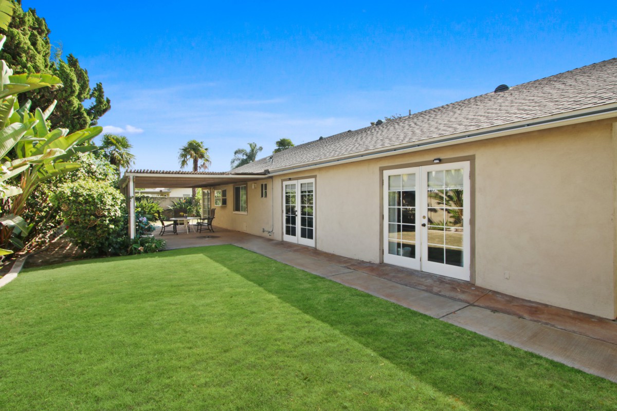 A cozy backyard featuring a well-maintained lawn and a covered patio area, perfect for outdoor relaxation.