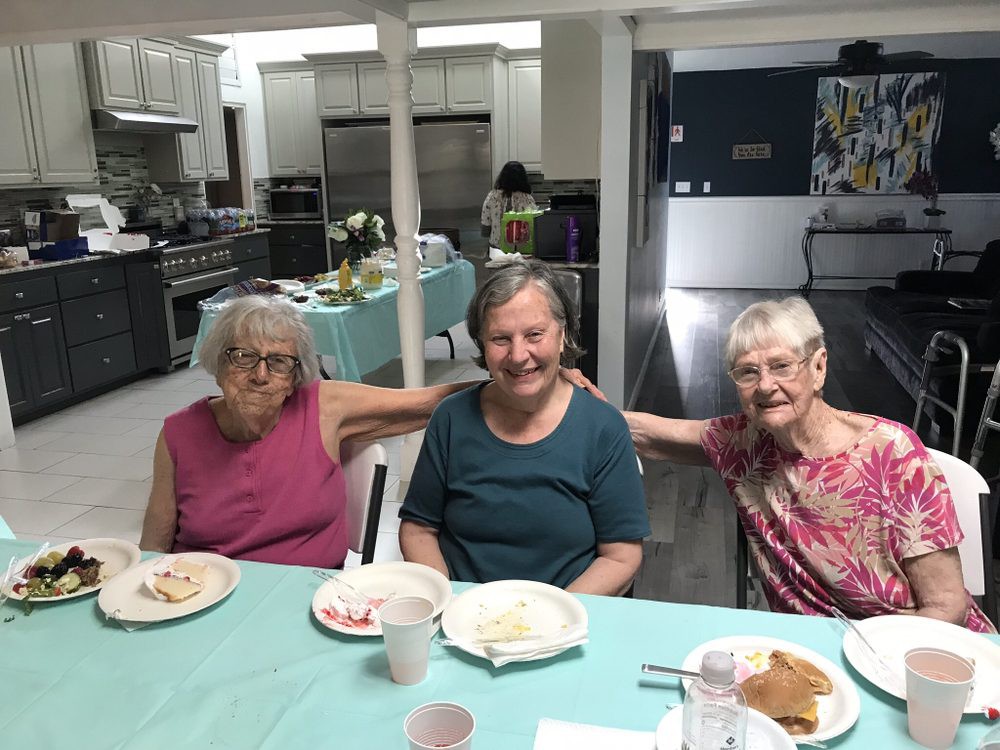 A group of three elderly women enjoying a meal together indoors.
