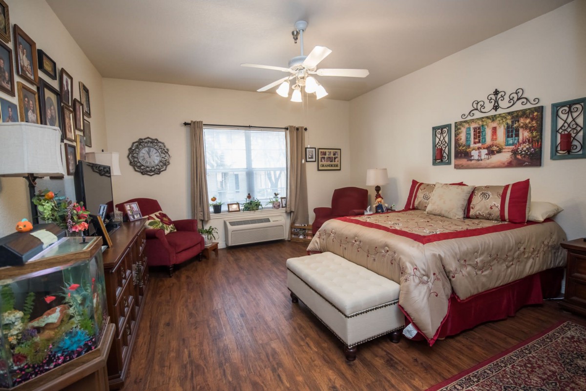 A cozy bedroom with a bed, comfortable chairs, and wooden flooring.