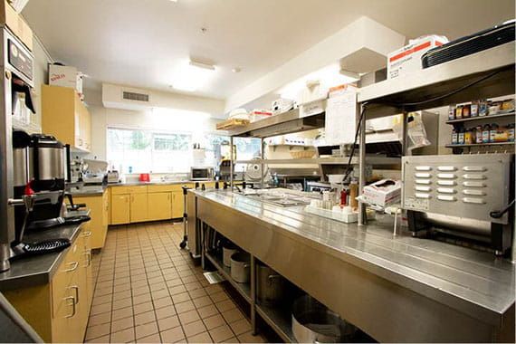 A spacious and well-organized commercial kitchen with stainless steel countertops and cooking equipment.