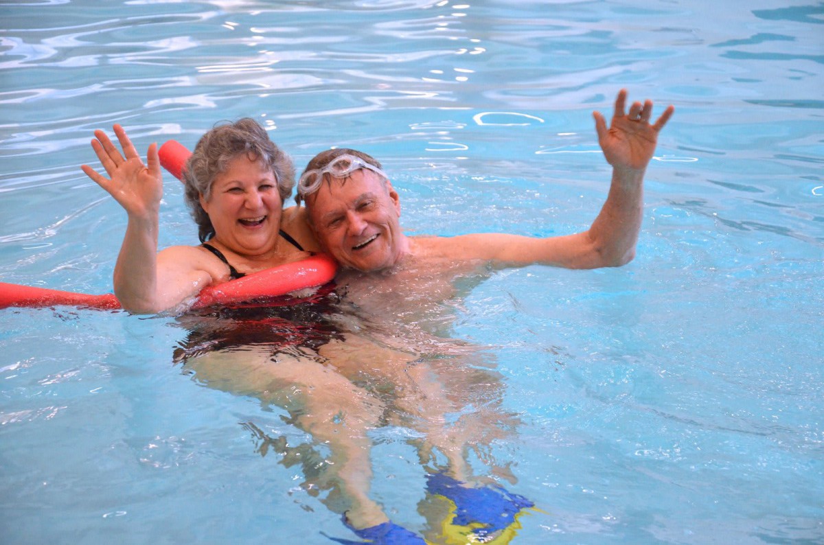 Senior couple enjoying a swim together in the pool.