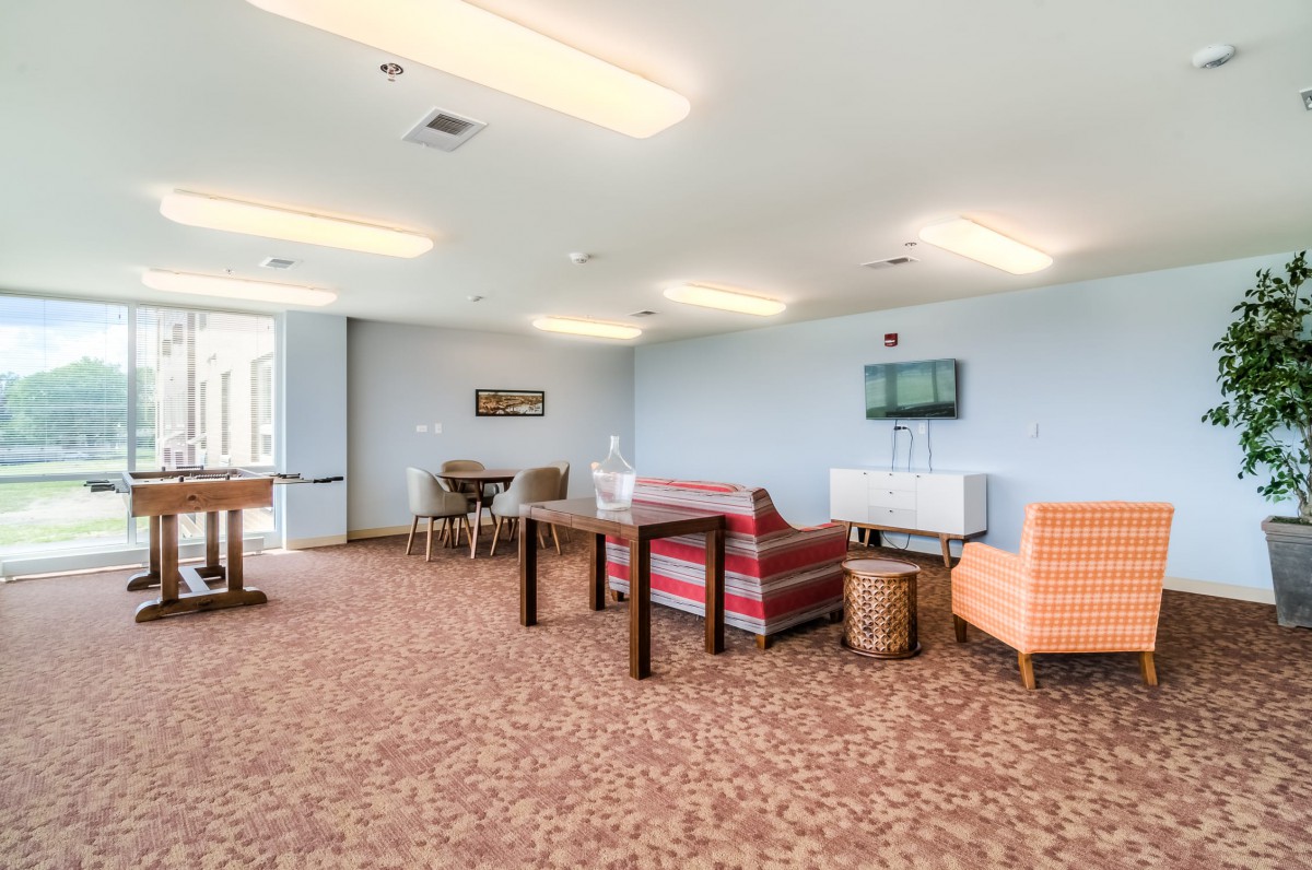 A spacious lounge area featuring various seating options, including sofas and chairs, with tables and carpeted flooring.