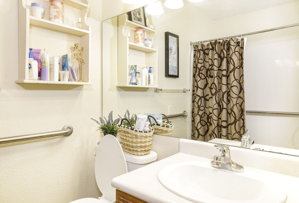 A well-organized bathroom with shelves, mirror, and decorative elements.